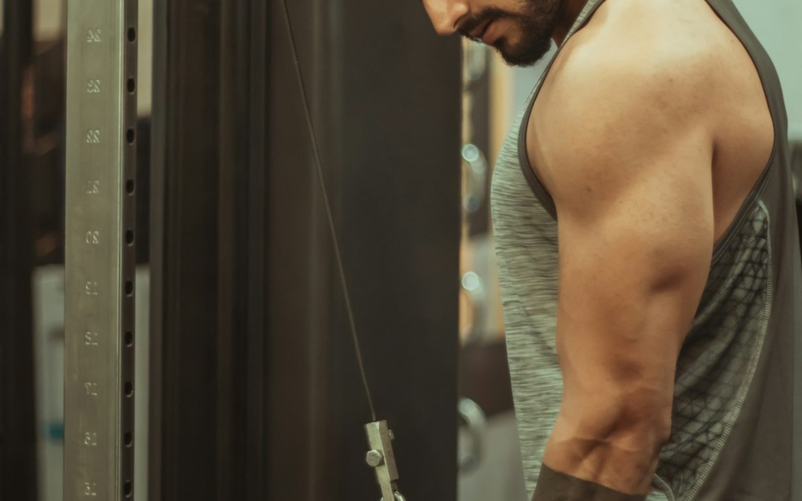 A row of cable machines and a lat pulldown station in a busy gym