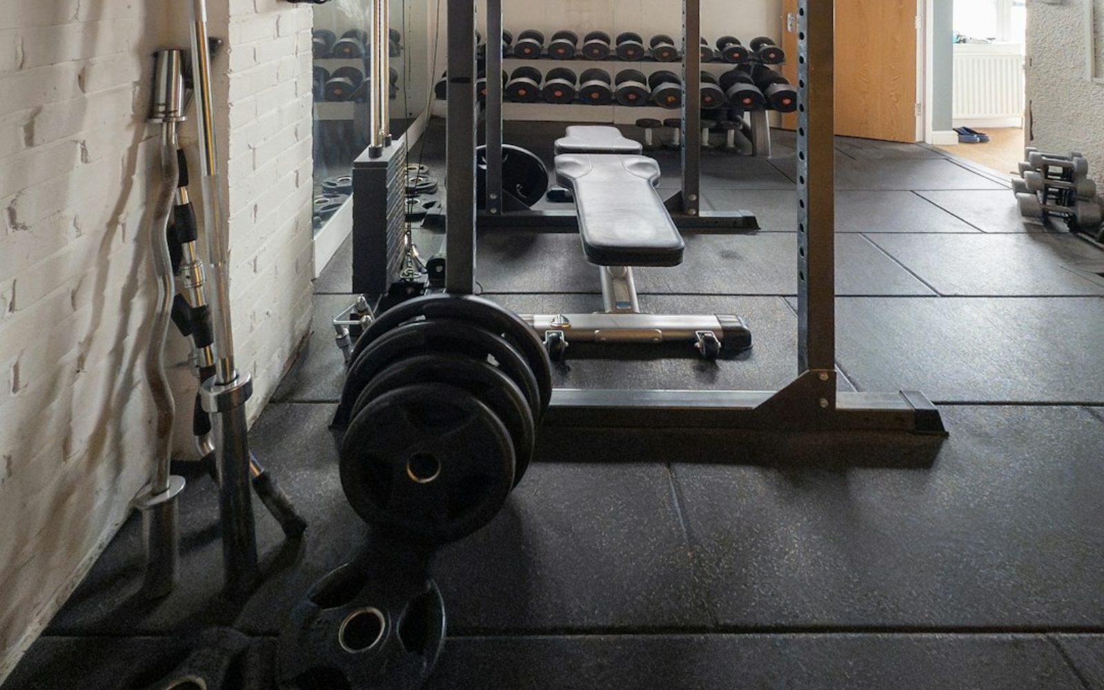 An empty gym floor with racks and benches in early morning light